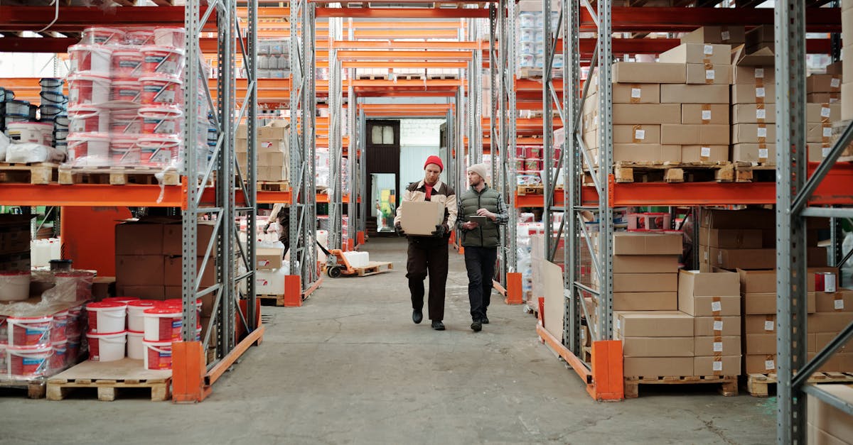 Two workers handle a package in a spacious warehouse surrounded by shelves stocked with boxes and products.